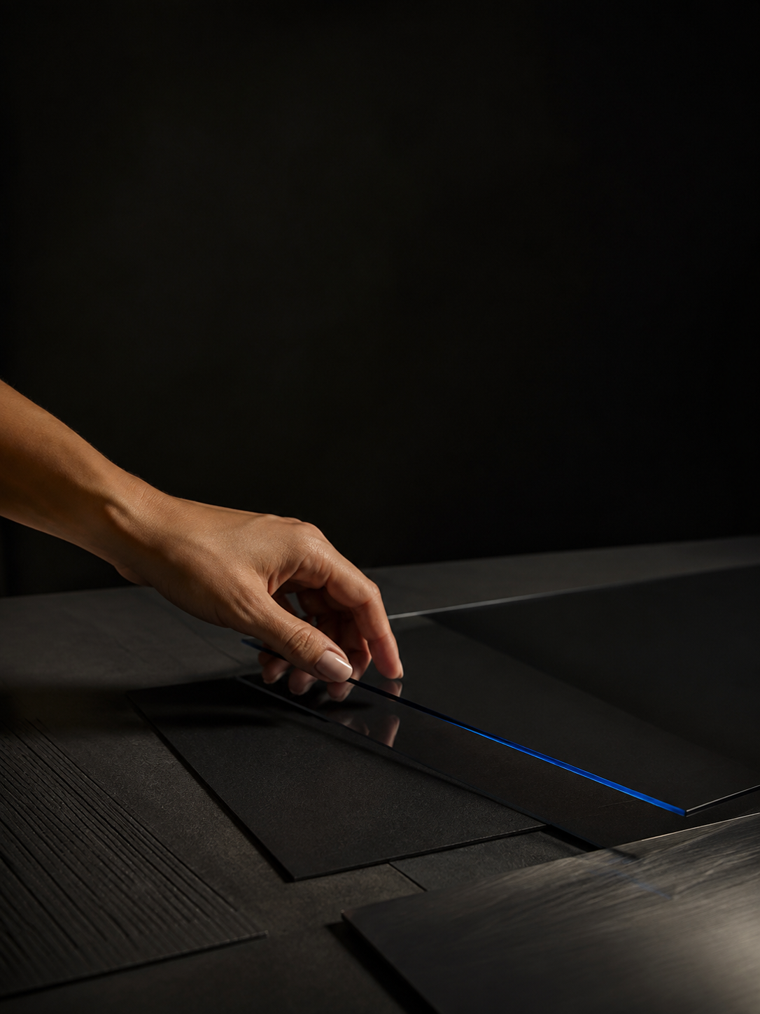 A hand arranging smoked glass on a dark creative surface